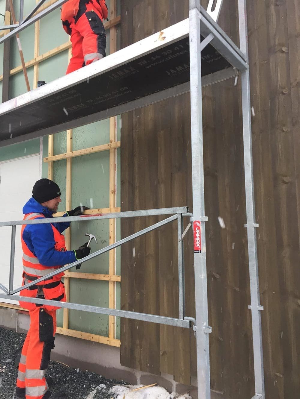 Fagarbeidere fra Skotnes Bygg AS monterer utvendig kledning på stillas – hytte med anneks i Åsenfjorden