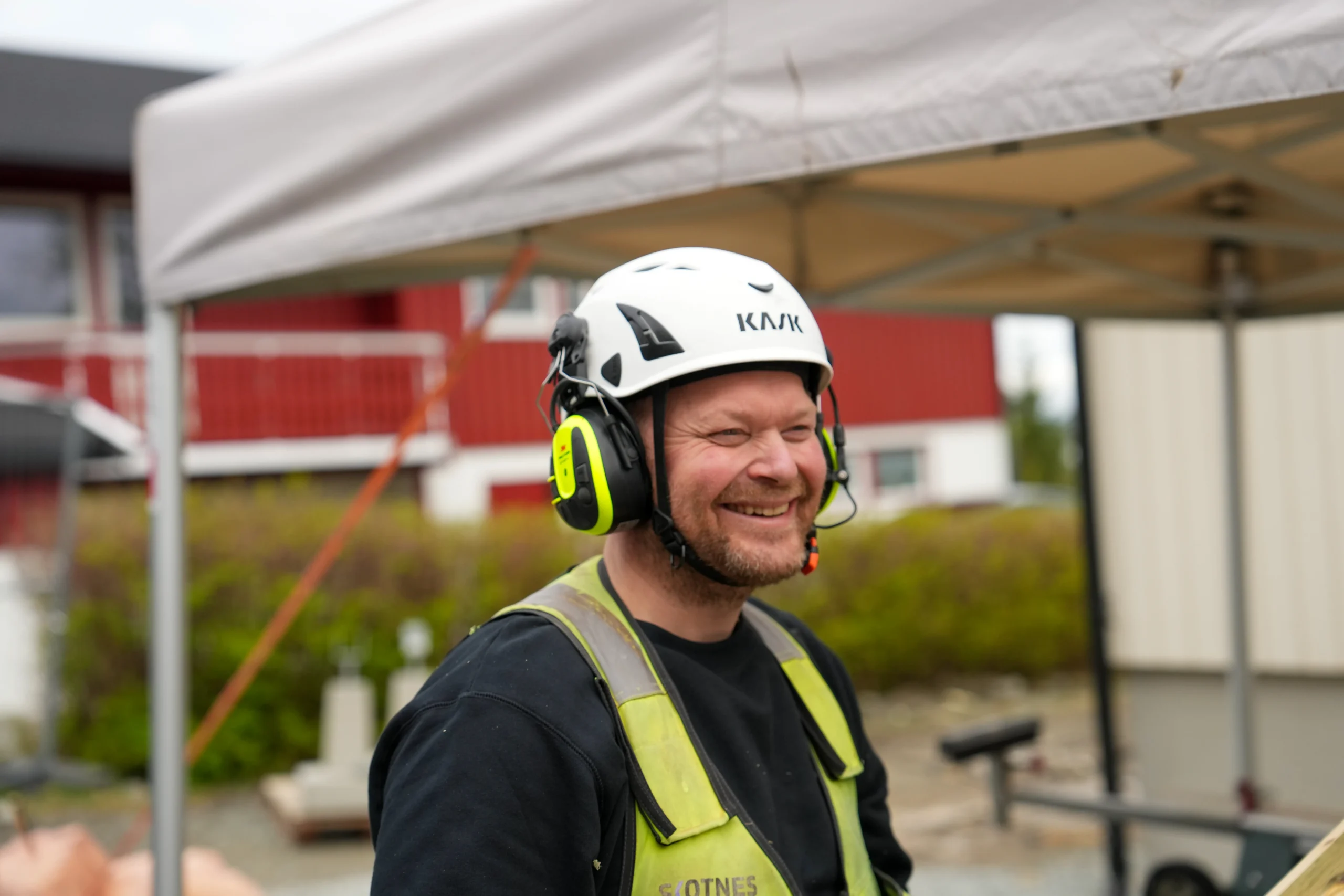 Knut Johan Skotnes – tørmer med mesterbrev fra Skotnes Bygg AS smiler med KASK-hjelm og vernejakke på byggeplass